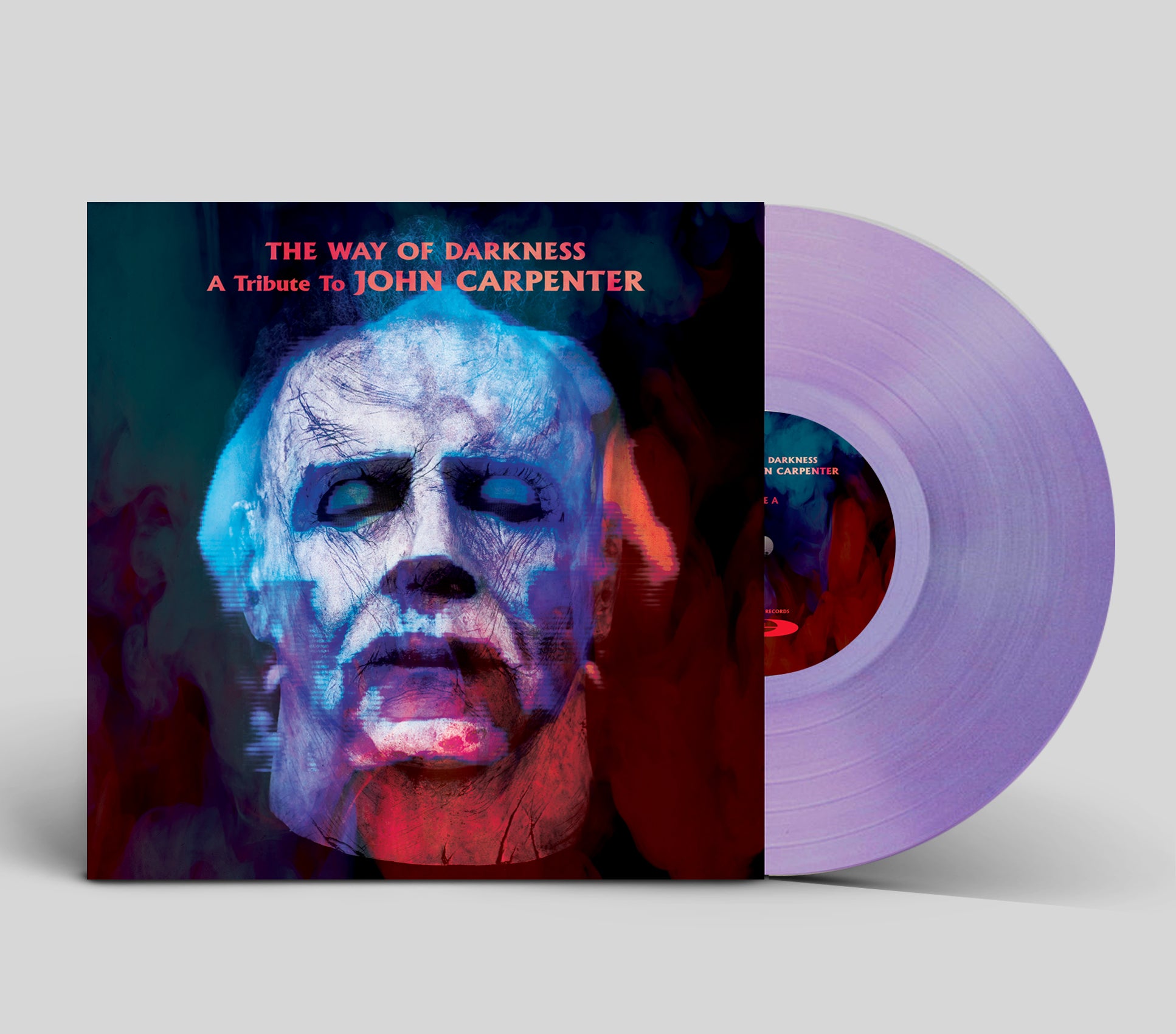 Vinyl record with a cover featuring a stylized face and text 'The Way of Darkness: A Tribute to John Carpenter' on a light gray background.